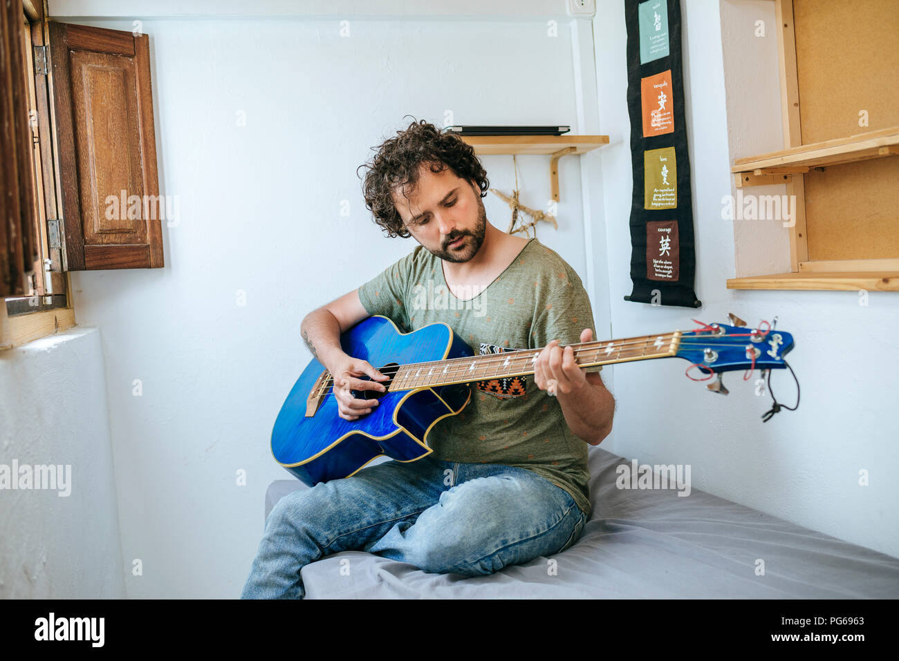 Spain, Man playing bass guitar in his room Stock Photo