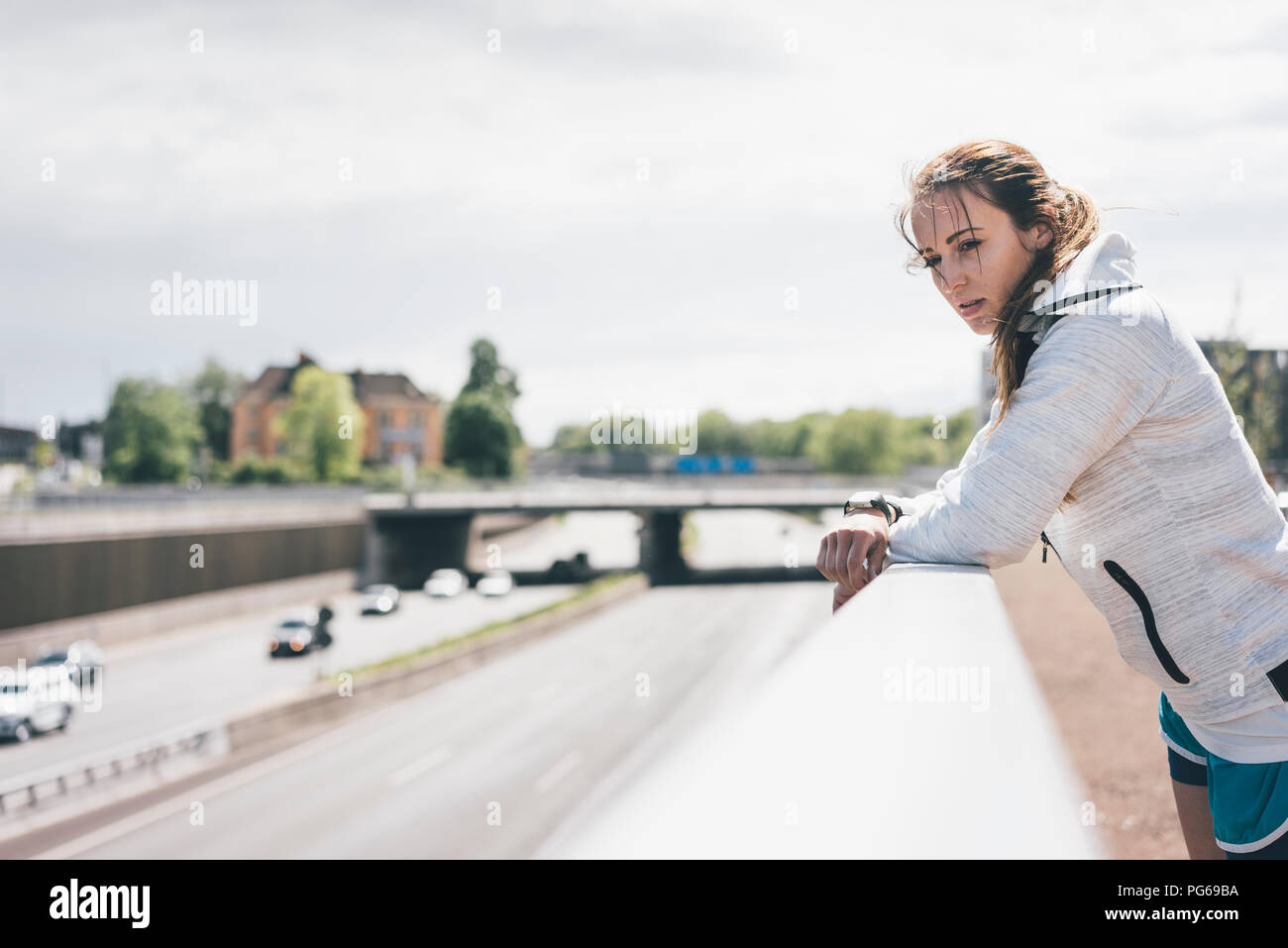 Sportive young woman leaning on railing at motorway Stock Photo