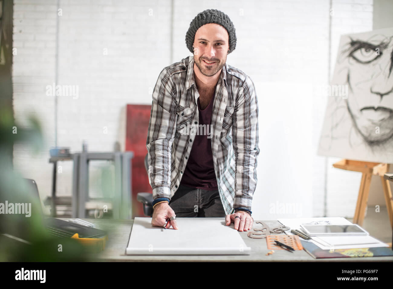 Portrait of confident artist standing at his desk in studio Stock Photo