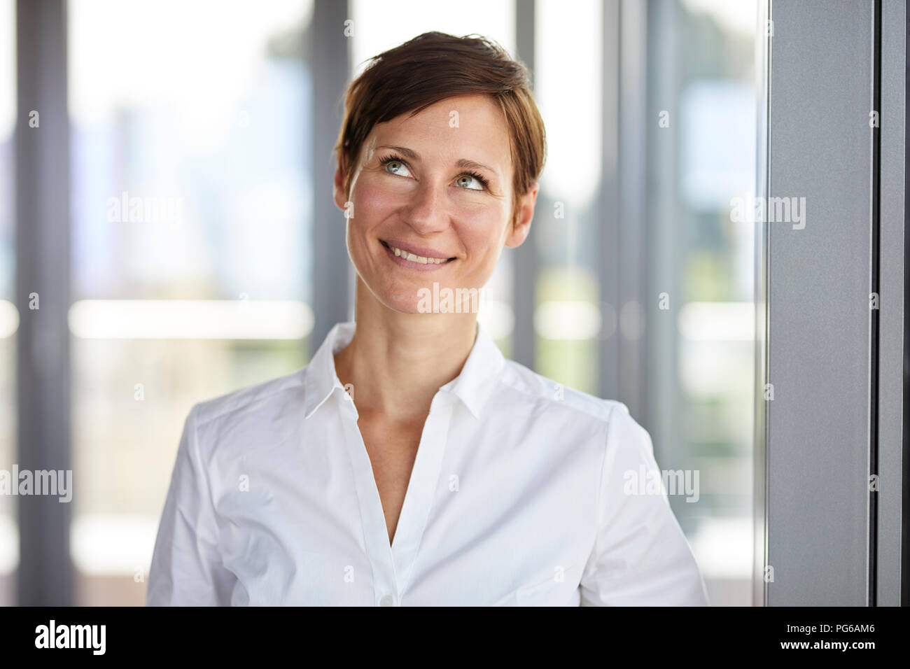 Portrait of smiling businesswoman in office looking up Stock Photo