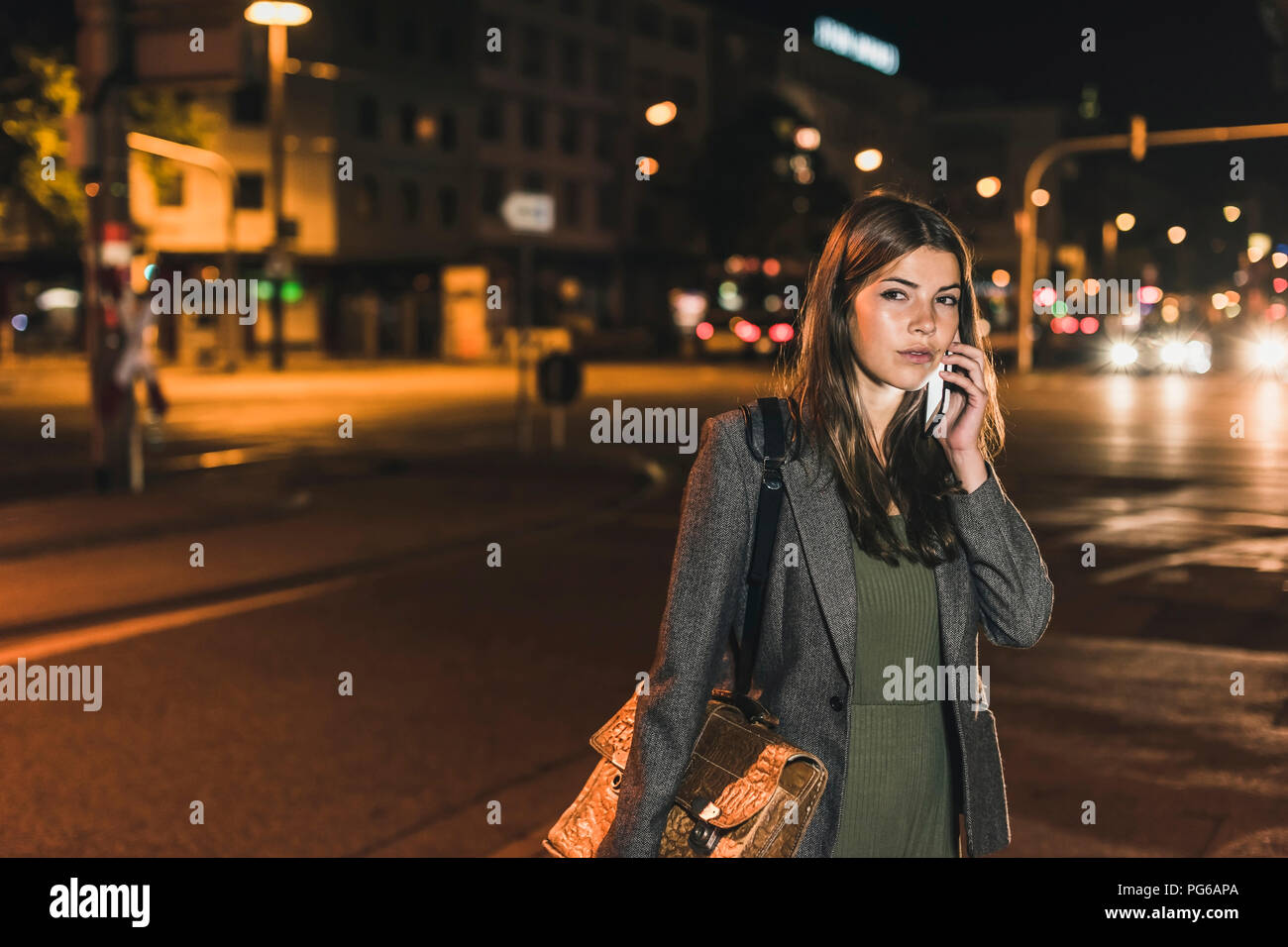 Portrait of young businesswoman with leather bag on the phone at night Stock Photo
