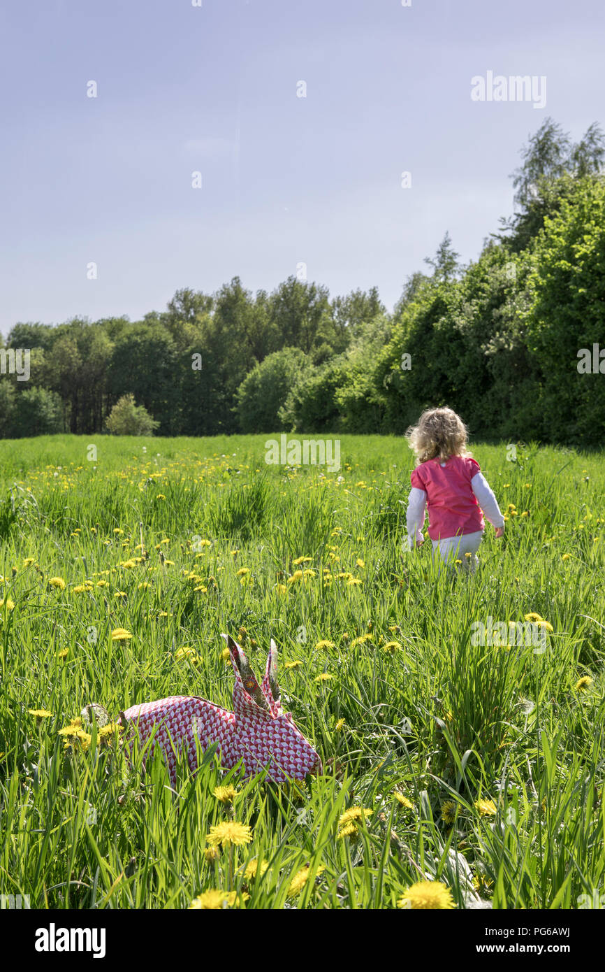 Little girl and origami rabbit on meadow Stock Photo