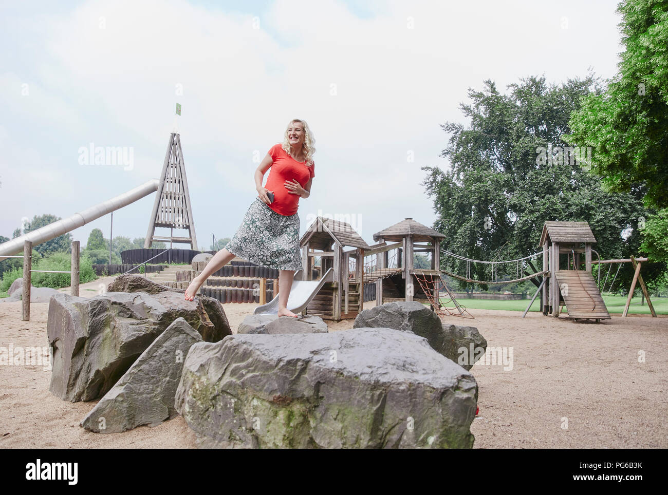 Happy pregnant woman balancing on a rock on playground Stock Photo