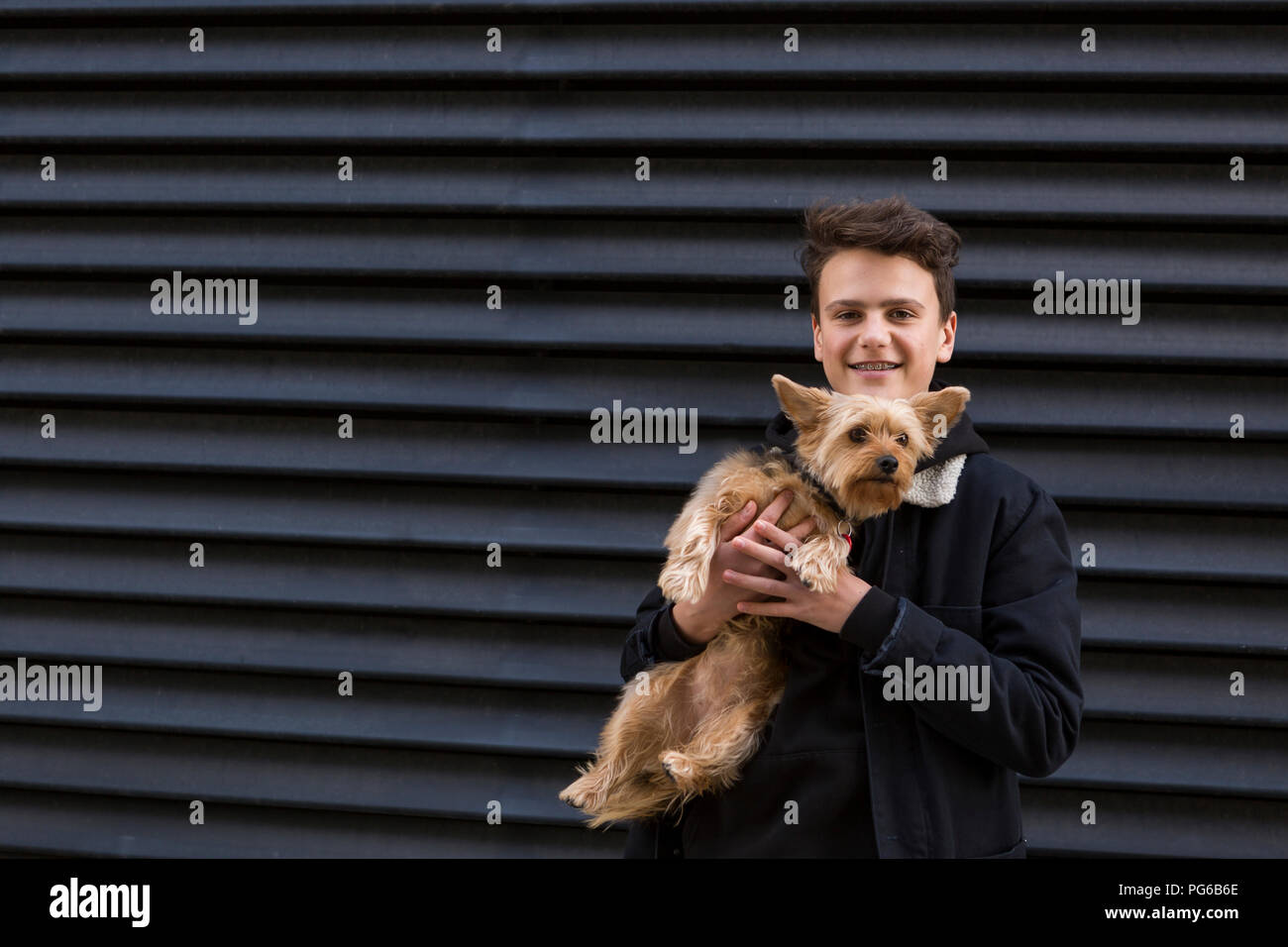Portrait of smiling teenage boy with his dog against black background Stock Photo