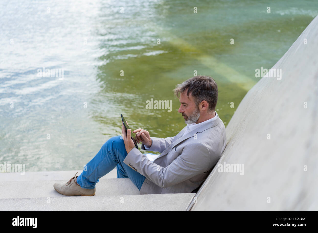 Businessman sitting on steps outdoors using tablet Stock Photo