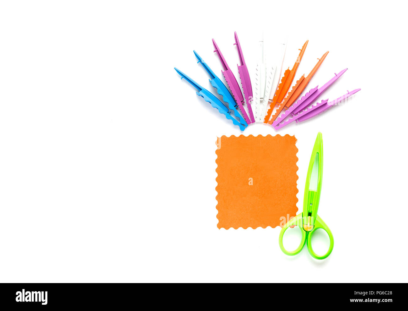 A green scissors with a wavy edge lie on a white background near an