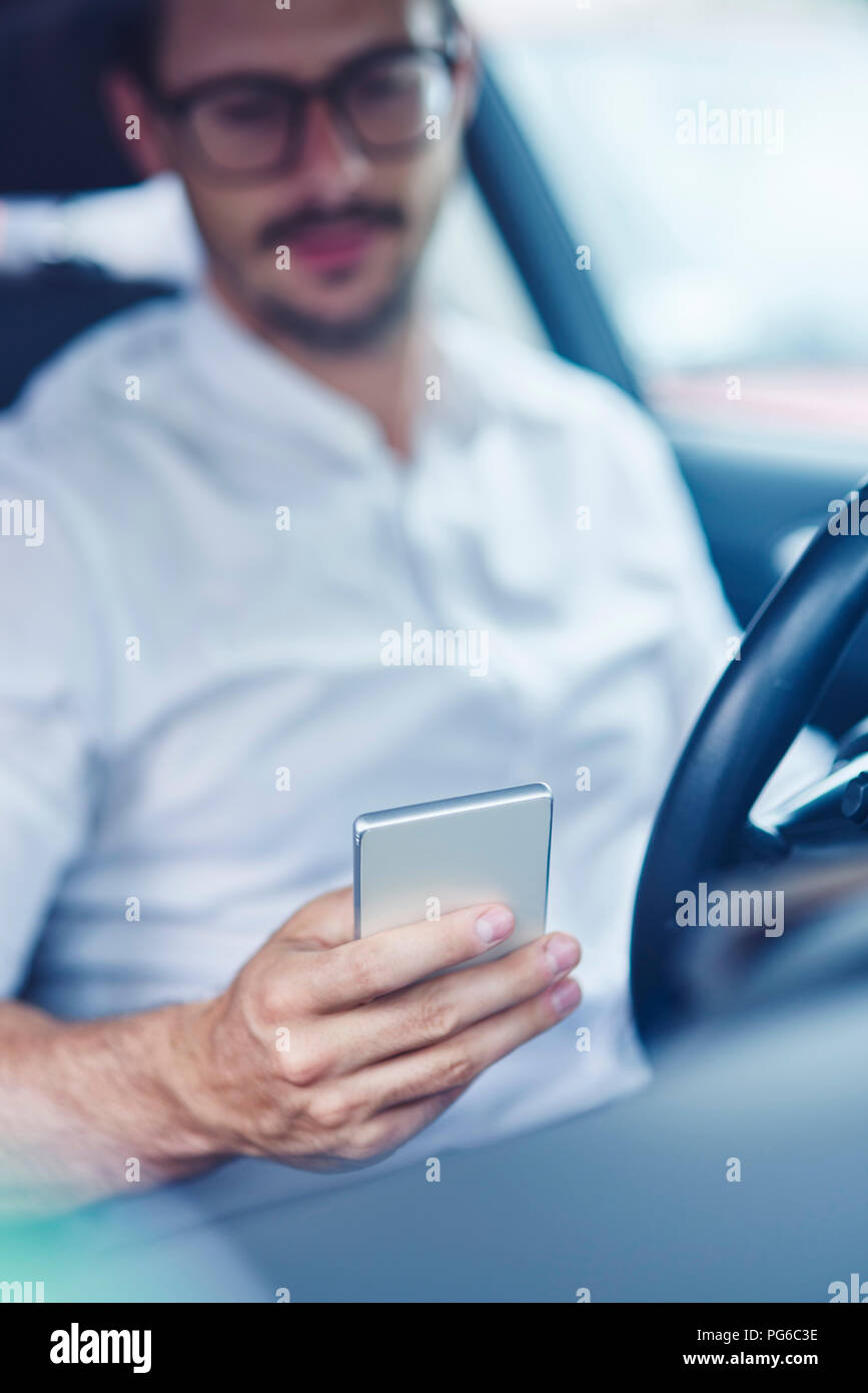Hand of businessman sitting in car holding cell phone Stock Photo