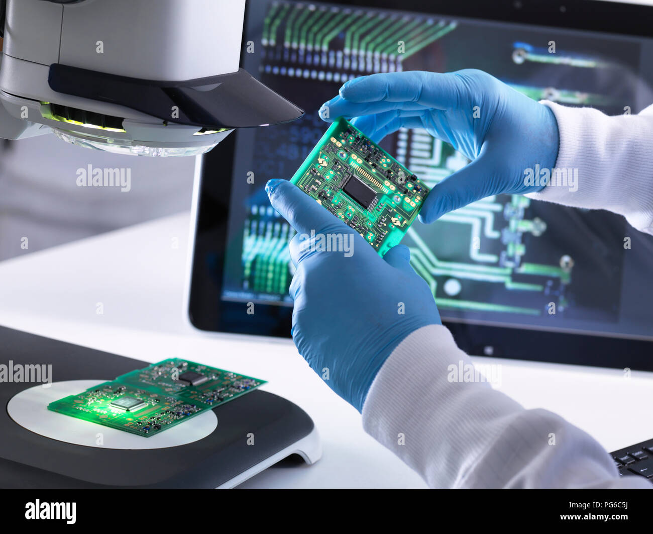 Engineer using a 3d stereo microscope for quality control in the manufacturing of circuit boards for the electronics industry Stock Photo