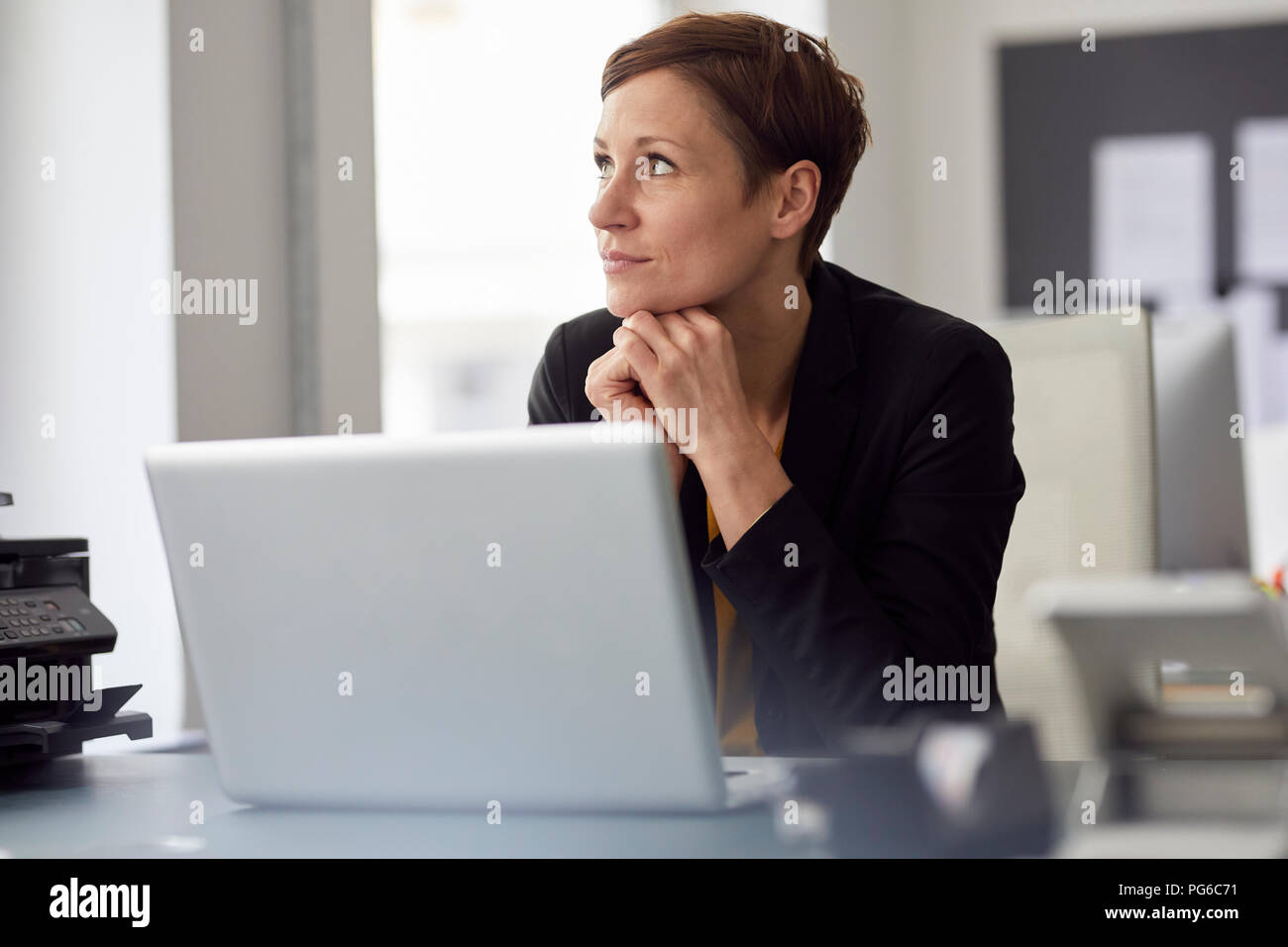 Businesswoman sitting in office, using laptop Stock Photo