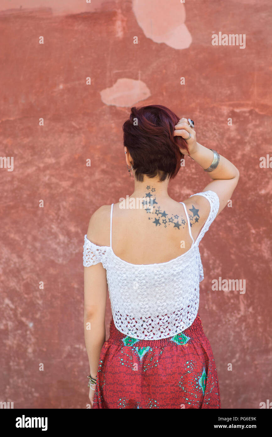 rear-view-of-a-young-woman-with-short-red-hair-hand-touching-head-stock