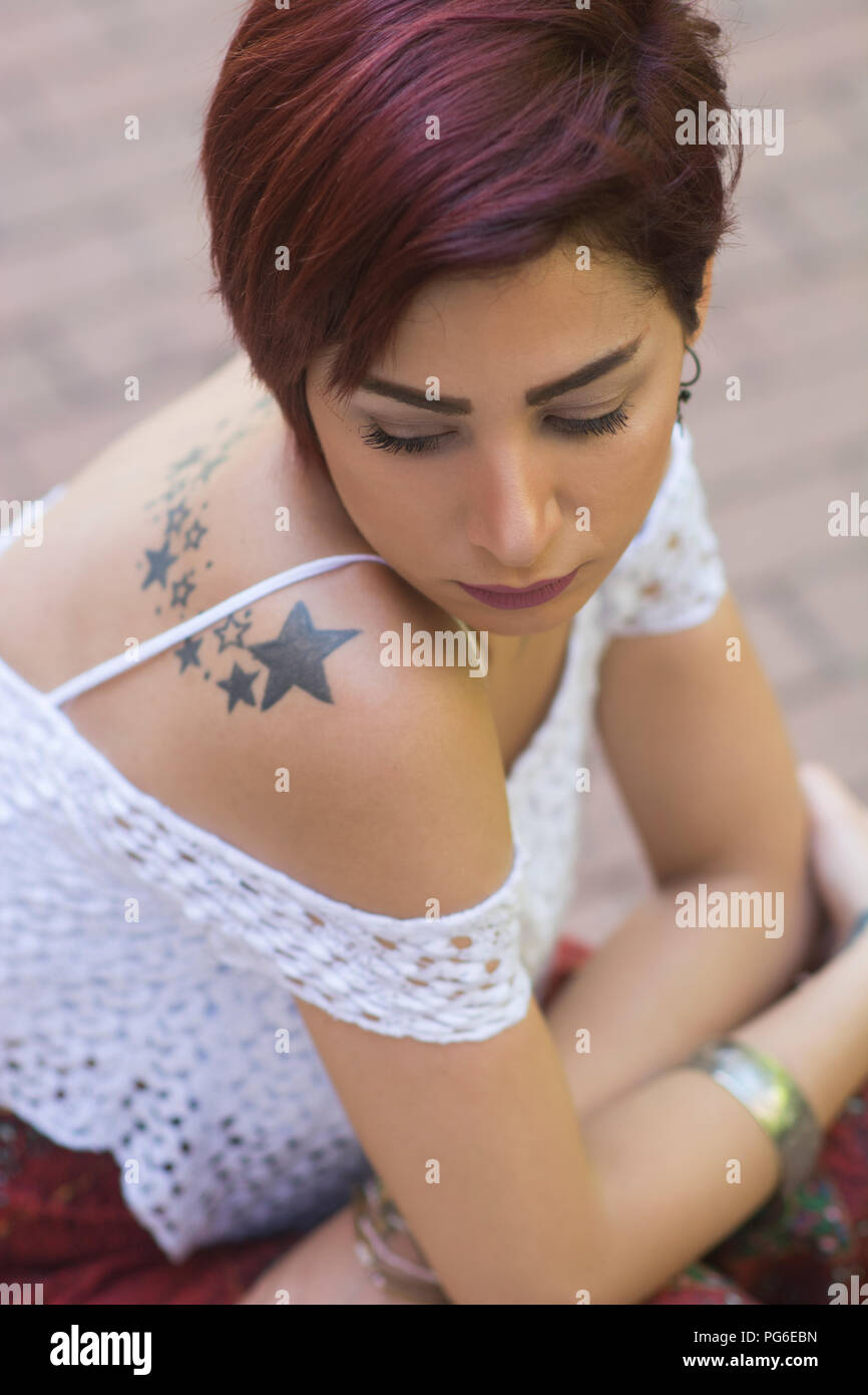 Sad woman sat outdoors Stock Photo
