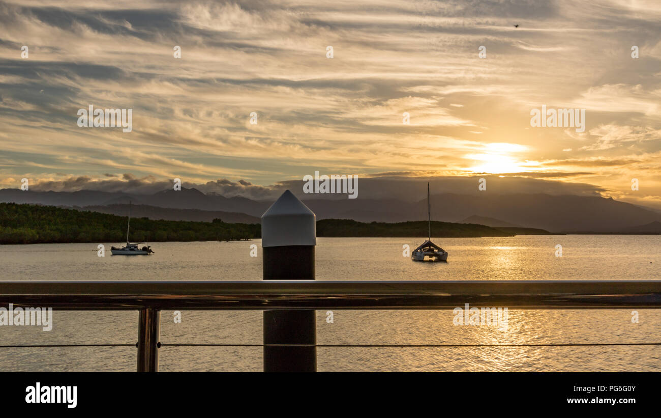 Sun setting against cloudy sky and marina pylon Stock Photo