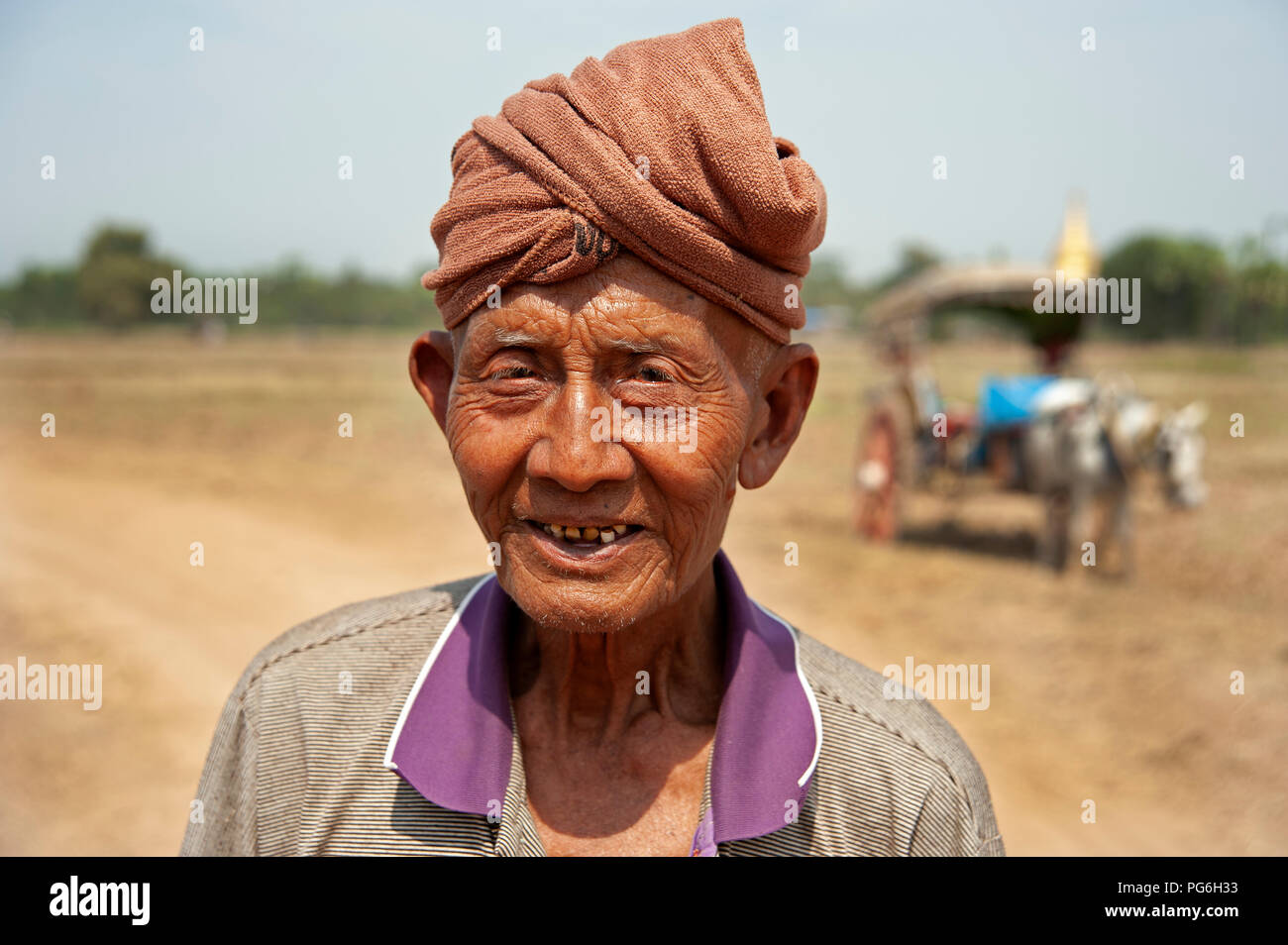 Portrait of an old Burmese man wearing a towel turban on his head with a horse and cart in the background Stock Photo