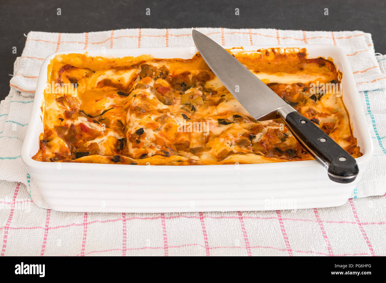 A vegetarian lasagne just out the ovan and ready to cut with the chefs