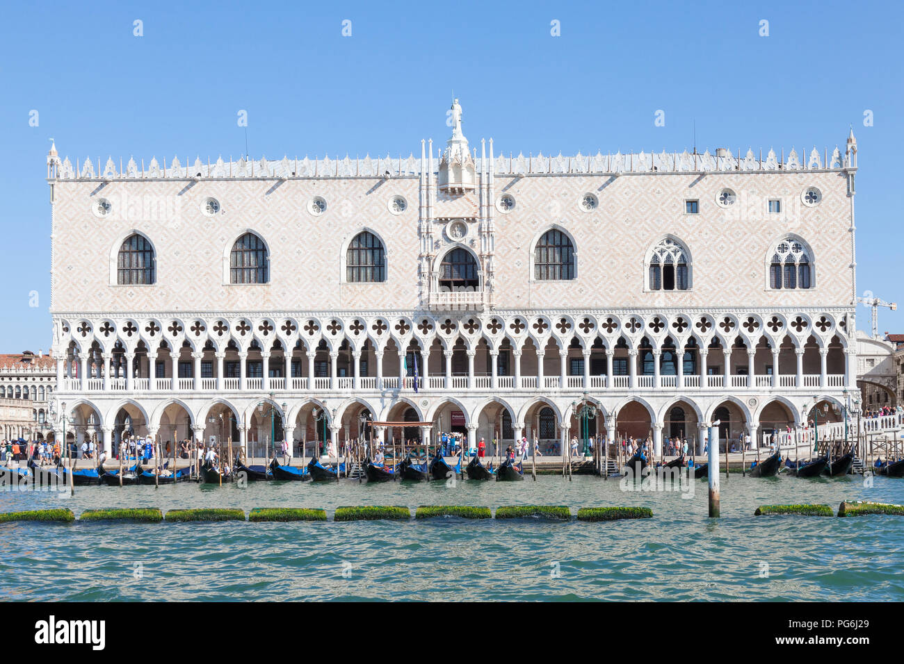 Doges Palace, Palazzo Ducale, Ducal Palace, San Marco, Venice, Veneto, Italy in morning light from the lagoon with gondolas and tourists, blue sunny s Stock Photo