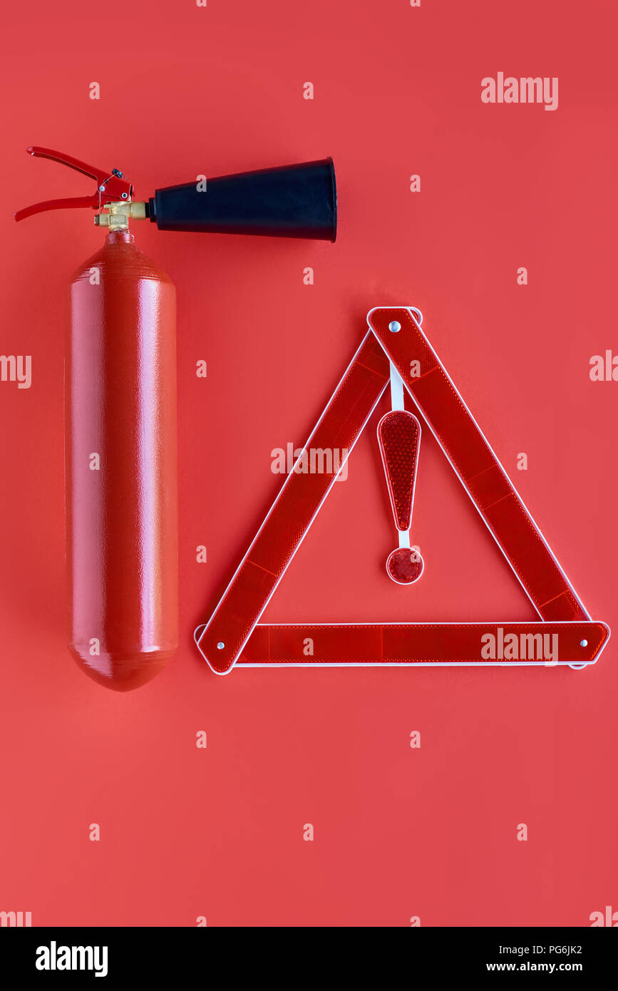 top view of fire extinguisher and warning triangle isolated on red ...