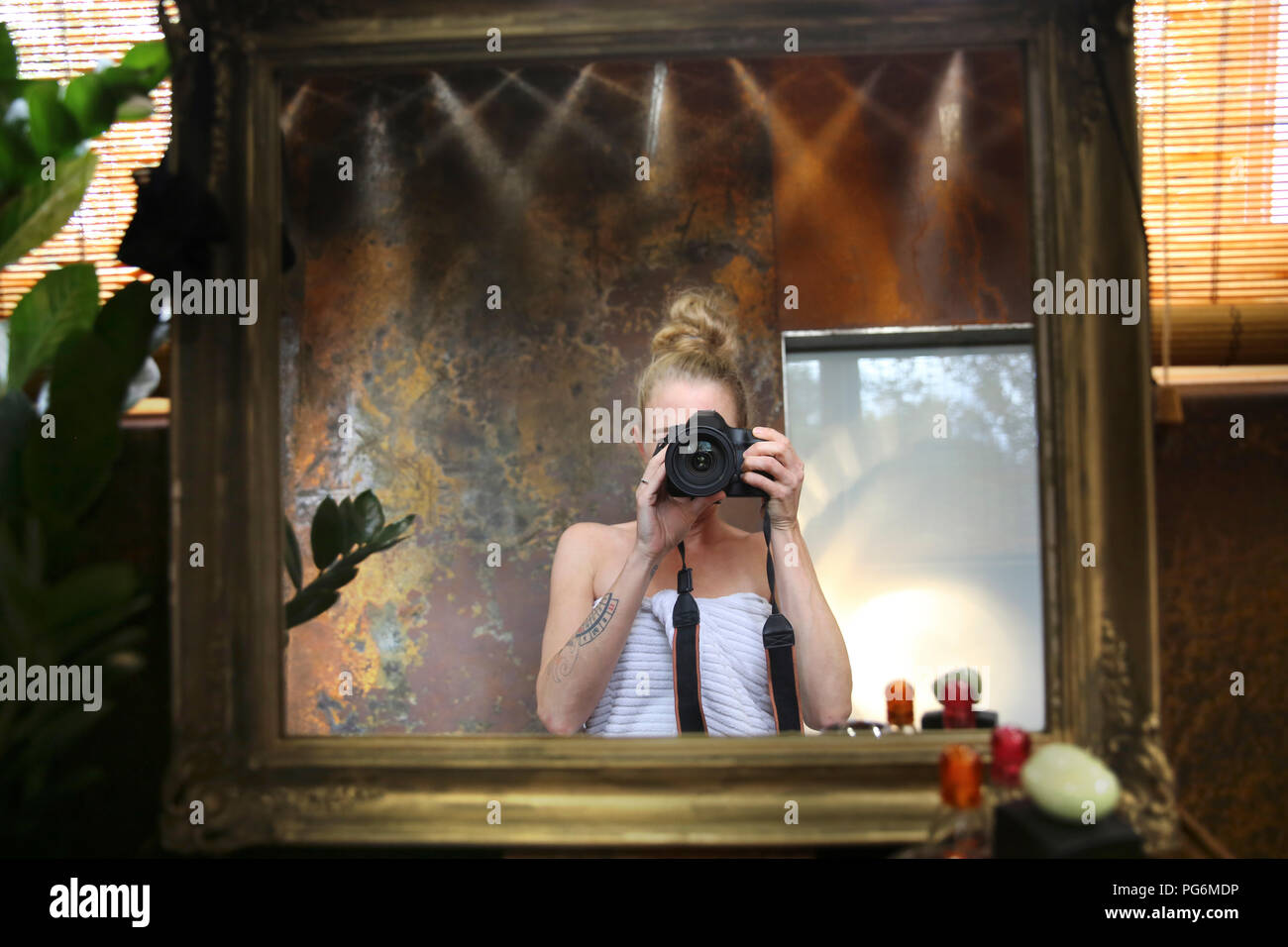 Mirror image of woman taking selfie with camera in bathroom Stock Photo