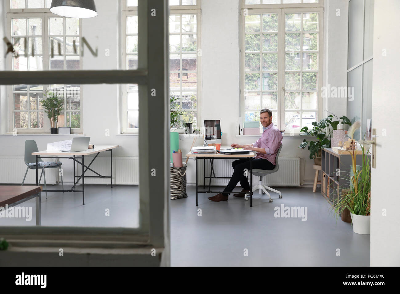 Man working at desk in a loft office Stock Photo