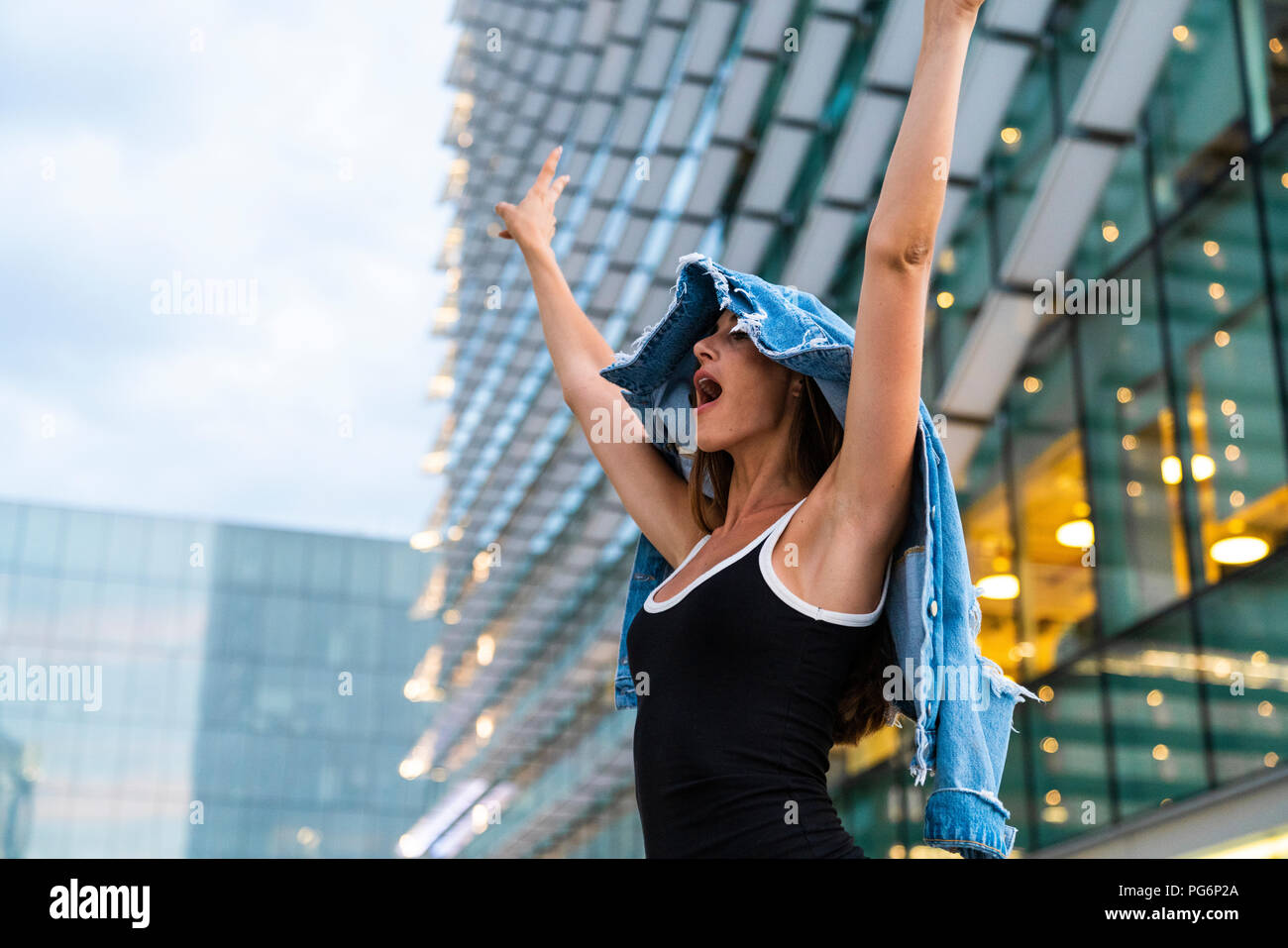 Carefree young woman wearing black dress in the city at dusk Stock Photo