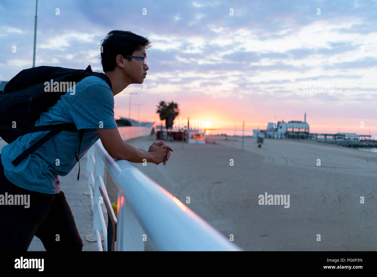 Young Chinese man with backpack looking at beach Stock Photo
