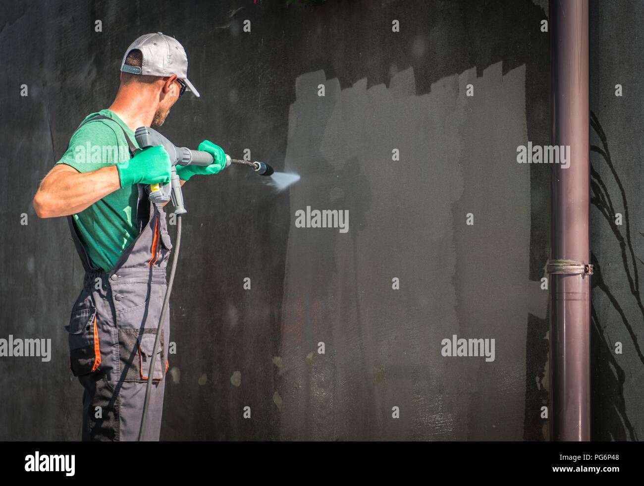 Building Elevation Pressure Washing by Worker with Power Washer. Refreshing House Outside Walls. Stock Photo