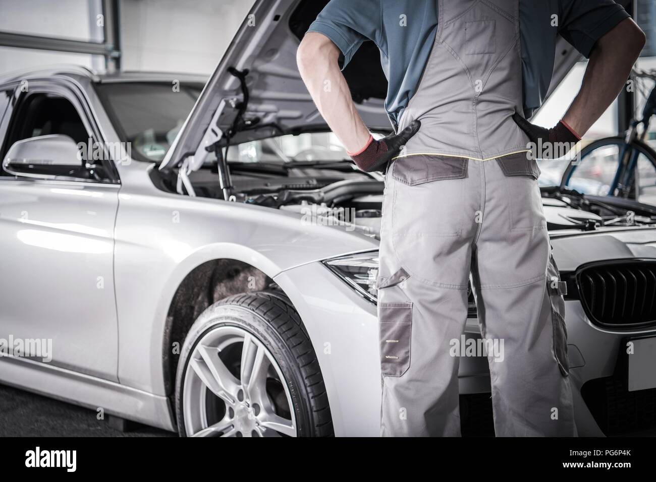 Modern Car Warranty Recall Fix. Mechanic in Front of the Vehicle in the