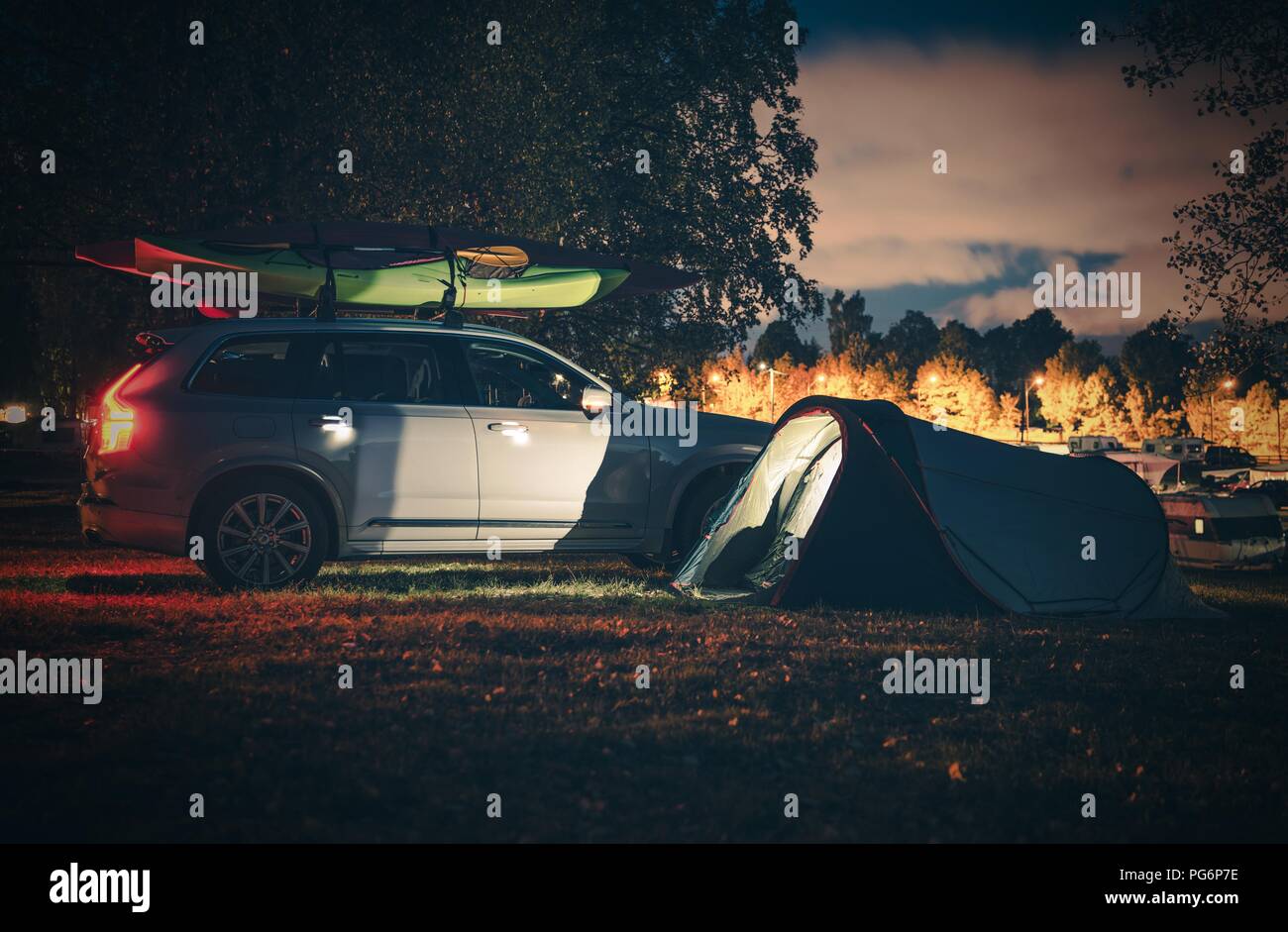 Vacation Campsite with Tent at Night. Modern Tent and Vehicle with Kayaks on the Roof Rack. Stock Photo