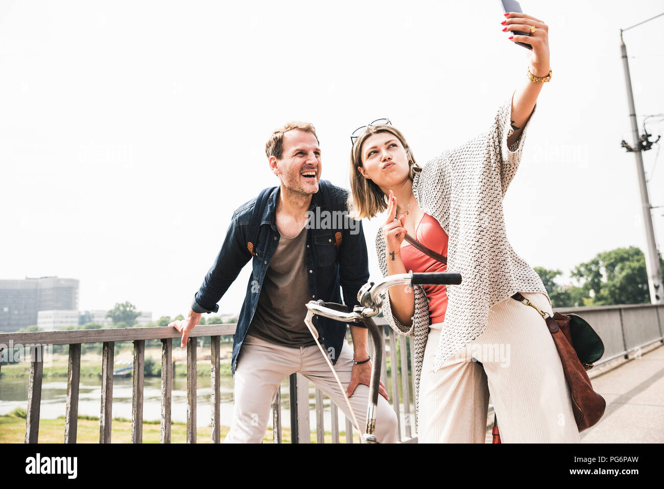 Happy couple taking a selfie on a bridge Stock Photo