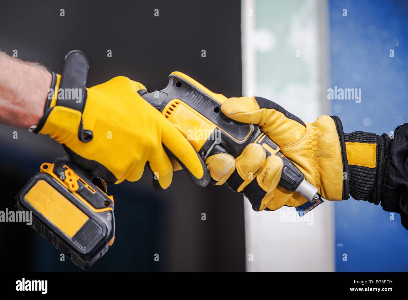 Sharing Construction Equipment Between Two Contractors in Safety Gloves. Closeup Photo. Drill Driver. Stock Photo