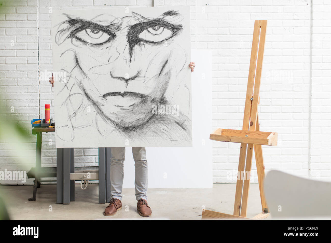 Obscured artist behind canvas holding drawing in studio Stock Photo