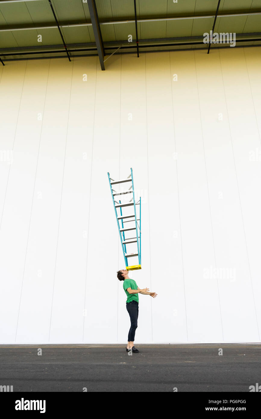 Acrobat balancing ladder on his face Stock Photo