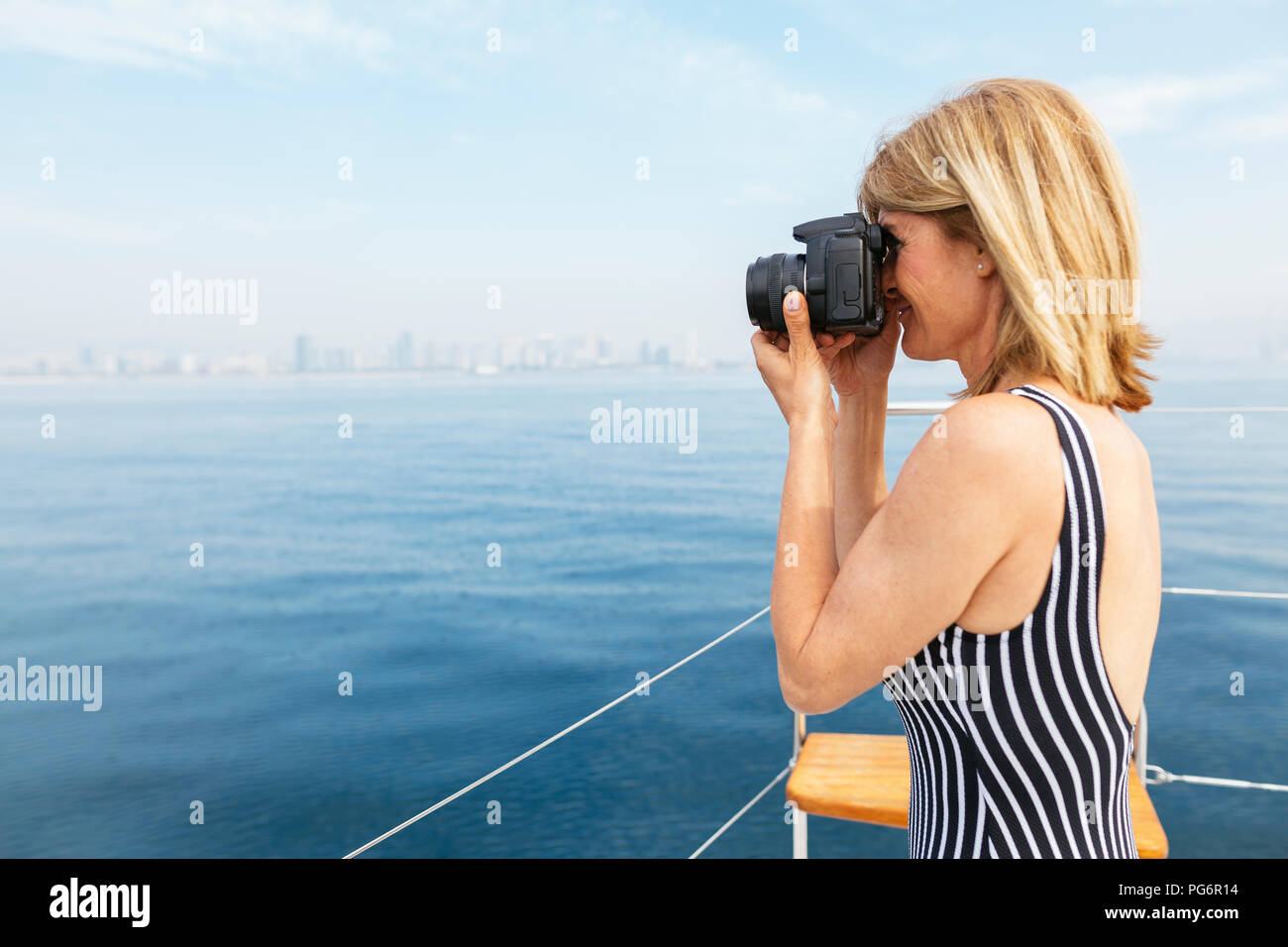 Mature woman on sailing trip photographing skyline of Barcelona Stock Photo