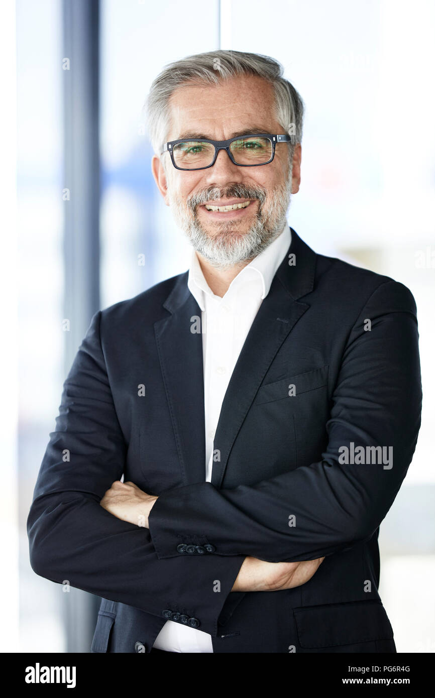 Portrait of smiling businessman standing at the window Stock Photo - Alamy