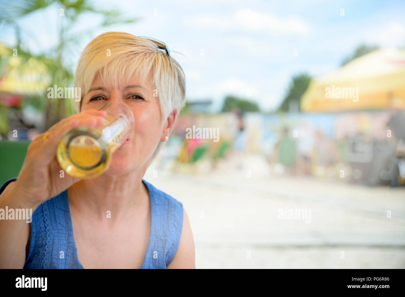Portrait of senior woman drinking beer at beach bar Stock Photo