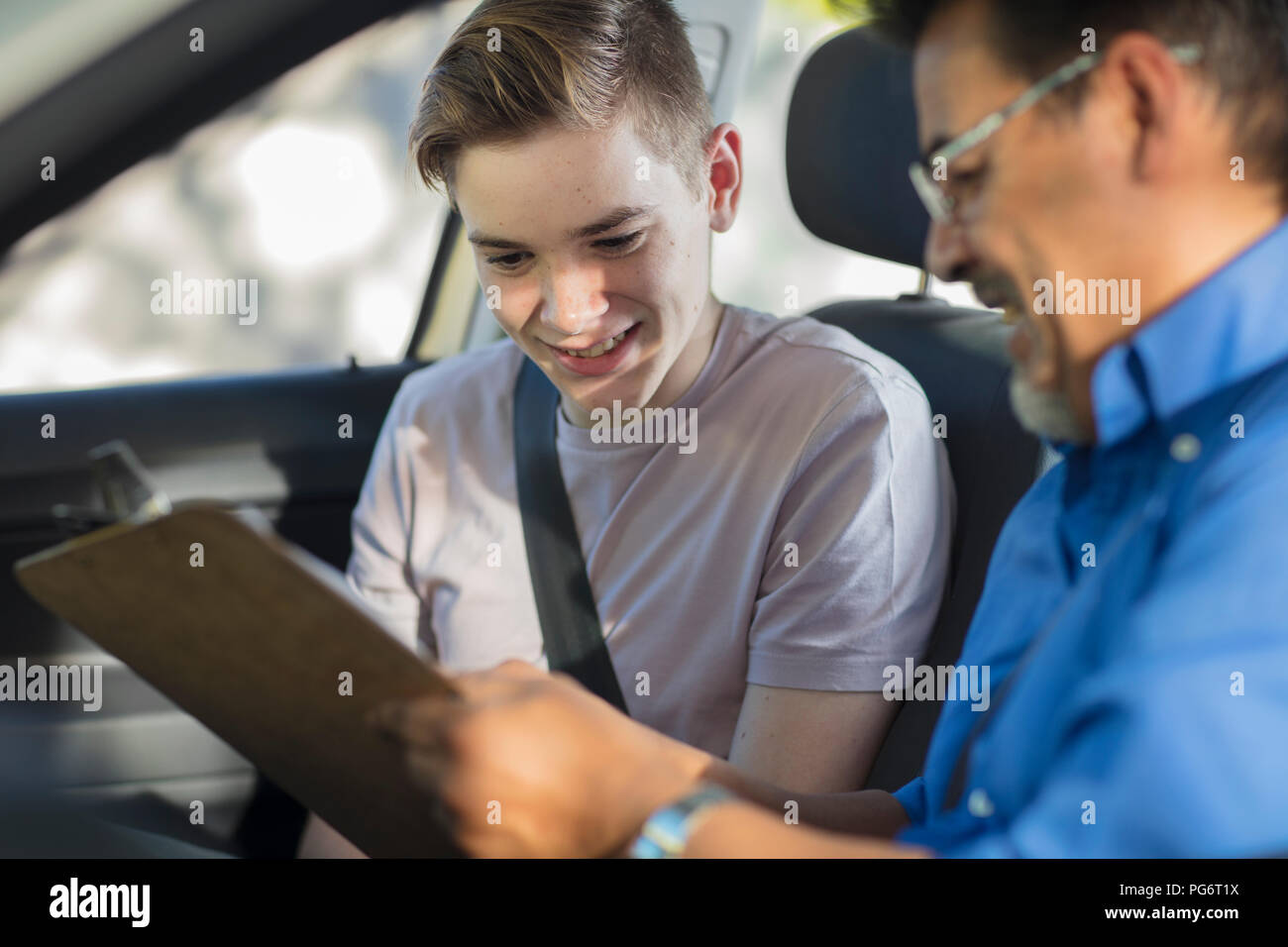 Learner driver with instructor in car looking at test script Stock Photo