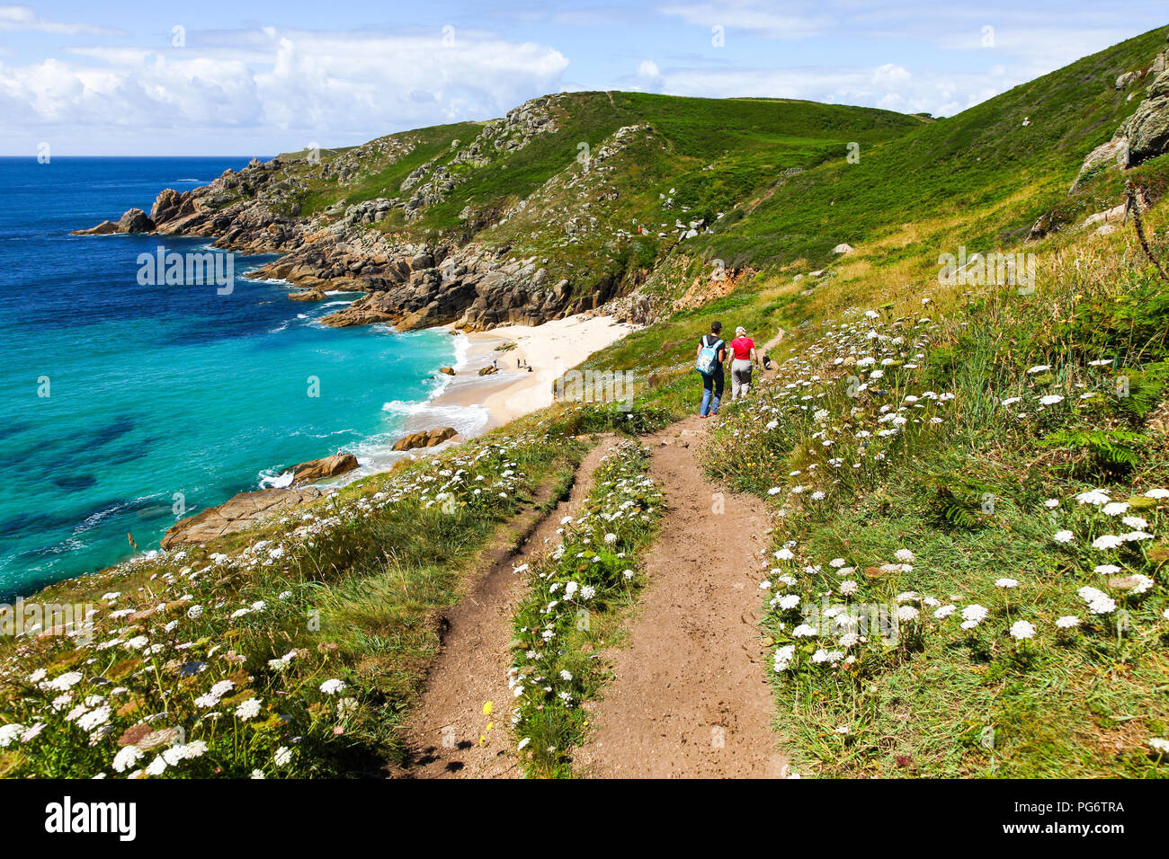 People walking on the footpath above Porthchapel or Porth Chapel beach, Cornwall, South West England, UK Stock Photo