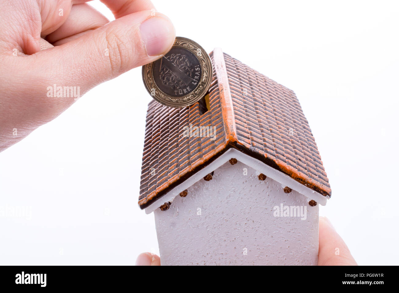 Hand dropping coin into the moneybox in the shape of a model house Stock Photo Alamy