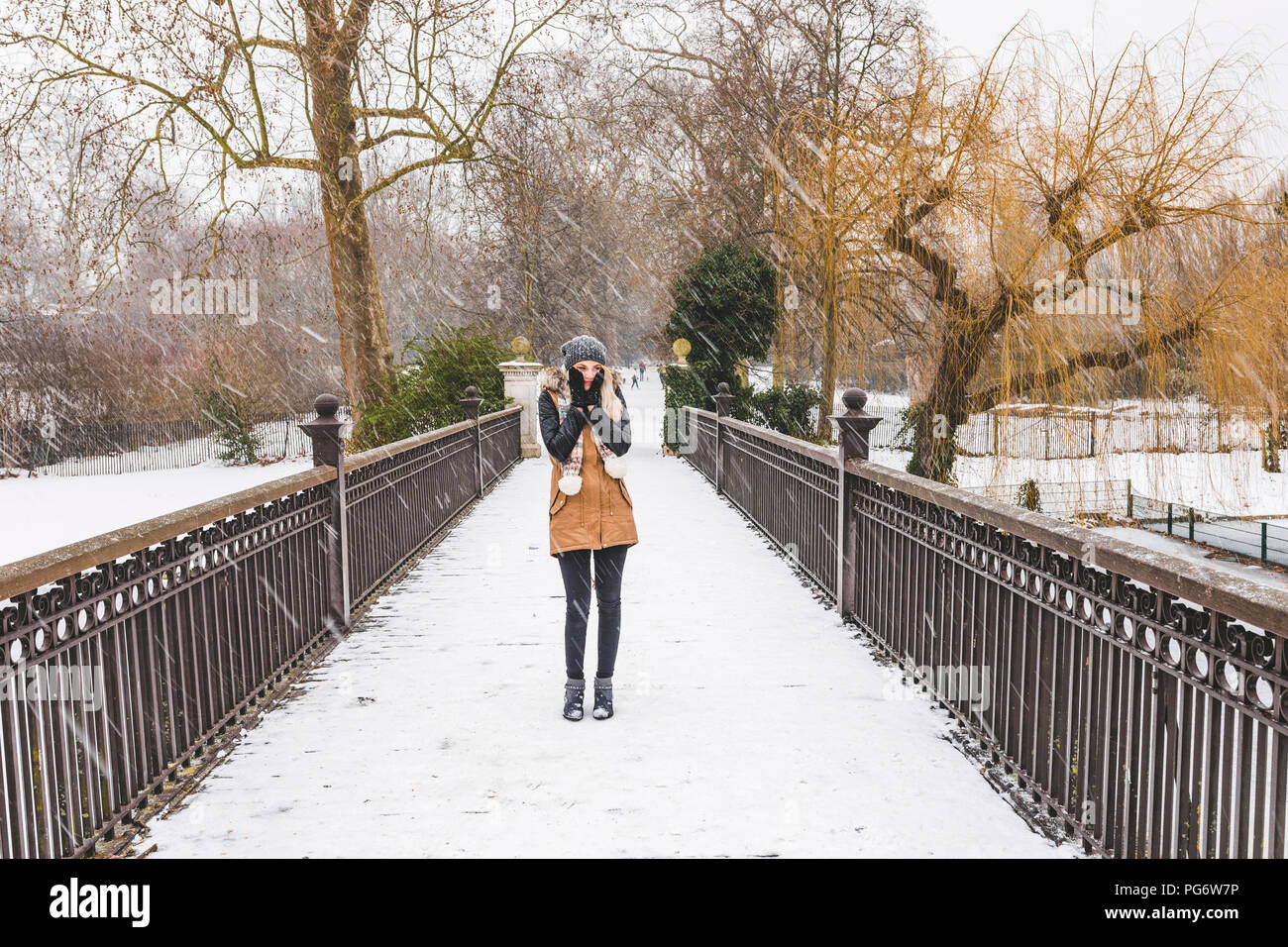 Teenage girl standing on footbridge in a park on a snowy day Stock Photo