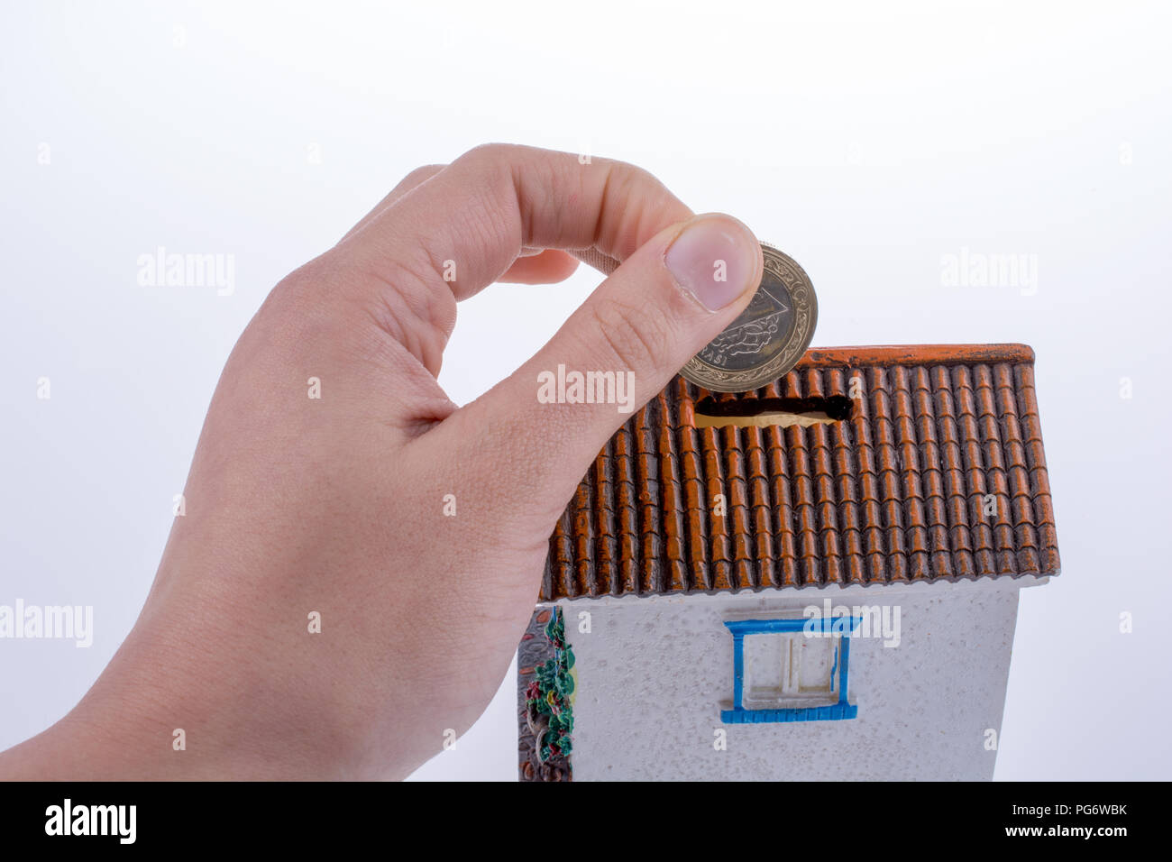 Hand dropping coin into the moneybox in the shape of a model house Stock Photo Alamy