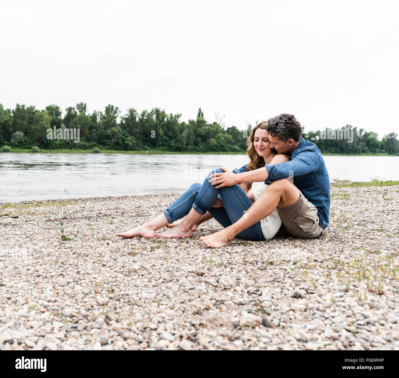 Affectionate couple sitting at the riverside Stock Photo - Alamy