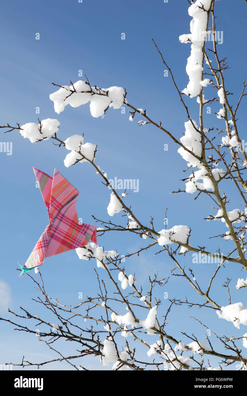 Origami bird on twigs with snow Stock Photo