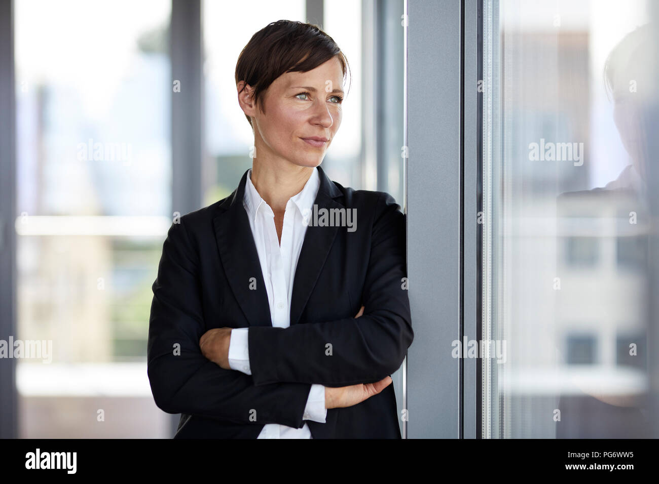 Businesswoman in office looking out of window Stock Photo