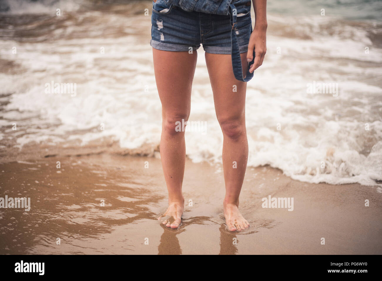 Legs of young woman in the water on a beach Stock Photo