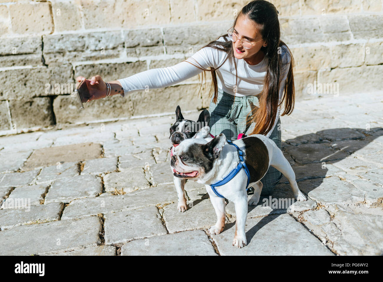 Young woman using smartphone, taking a selfie with her dogs Stock Photo