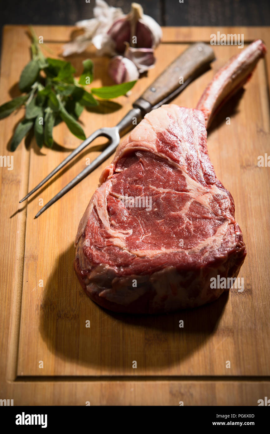 Raw tomahawk steak, garlic and herbs Stock Photo
