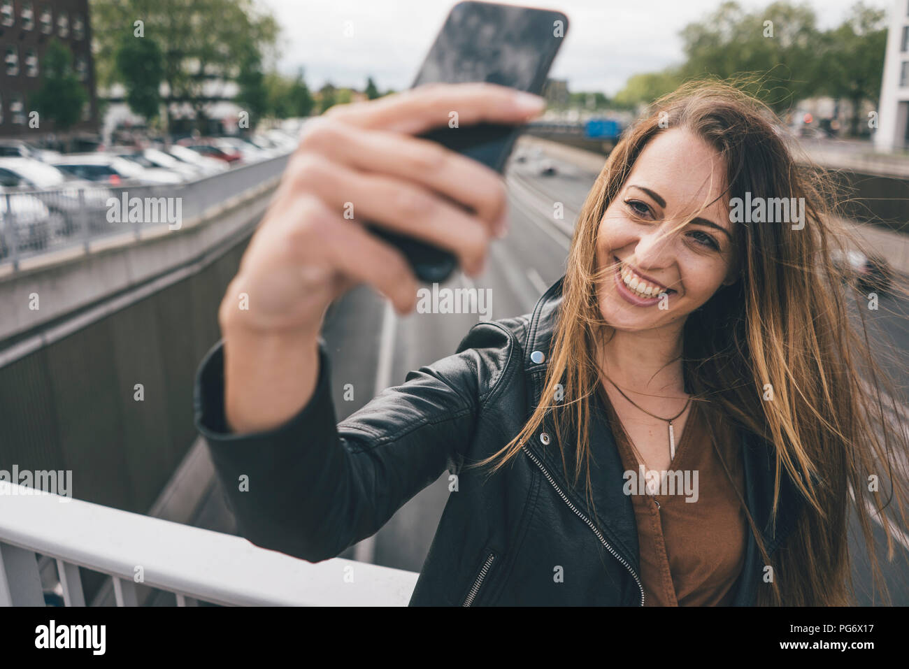 Smiling young woman taking a selfie on motorway bridge Stock Photo
