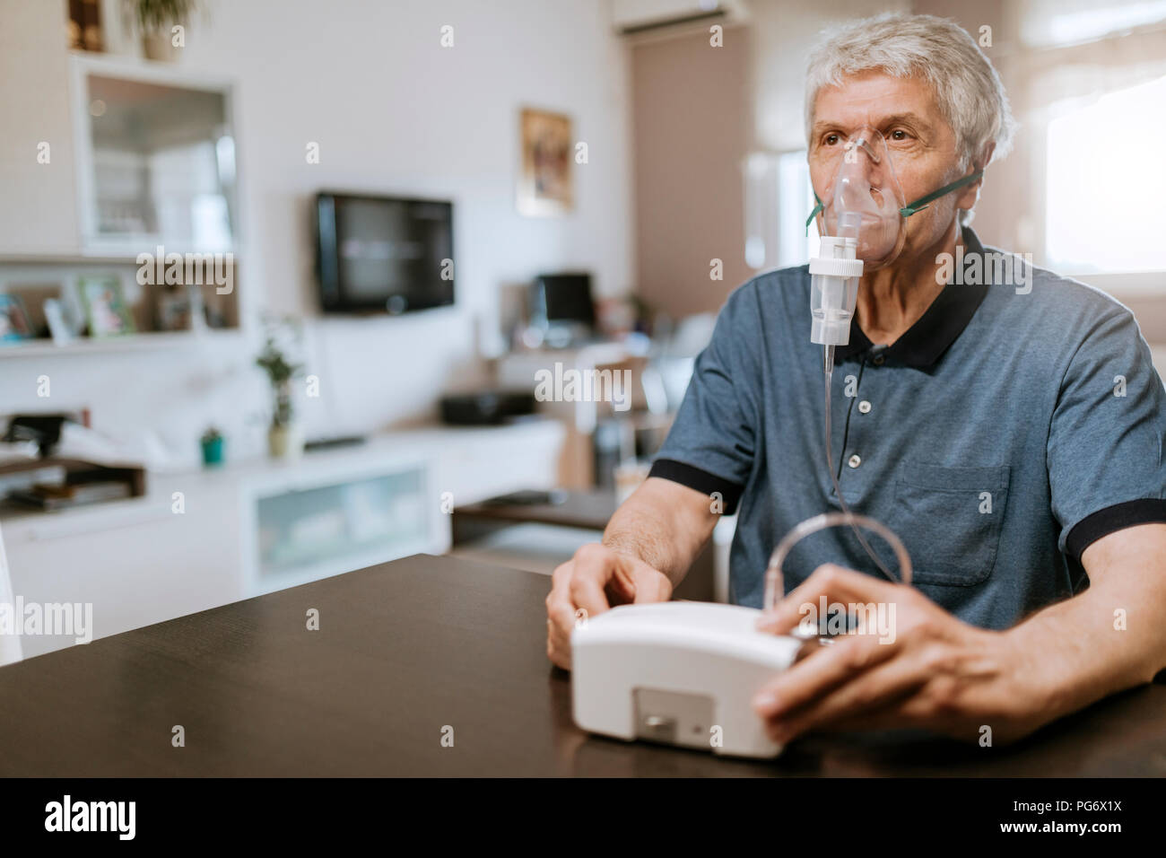 Senior man using inhaler at home Stock Photo
