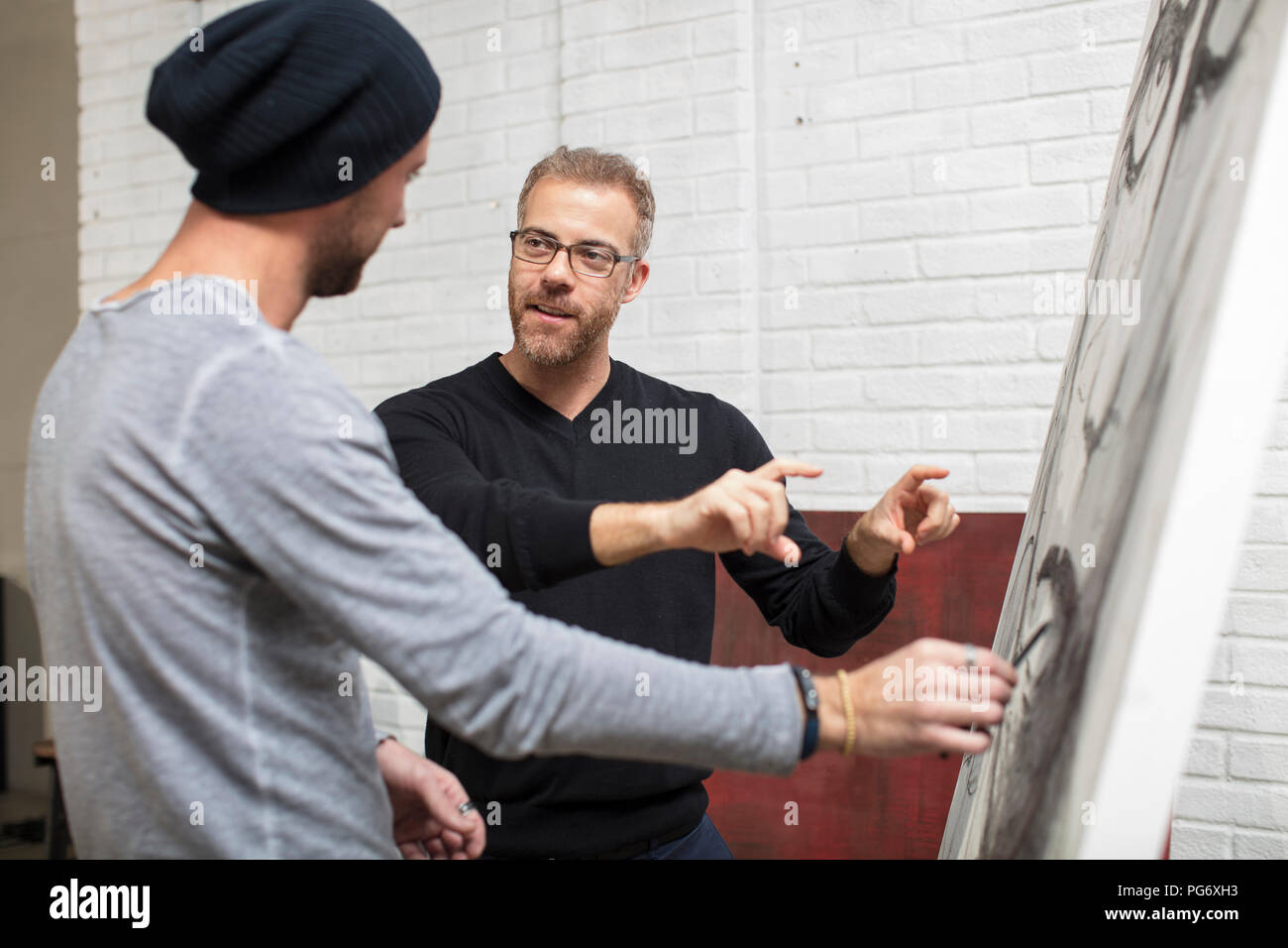 Artist discussing drawing with man in studio Stock Photo