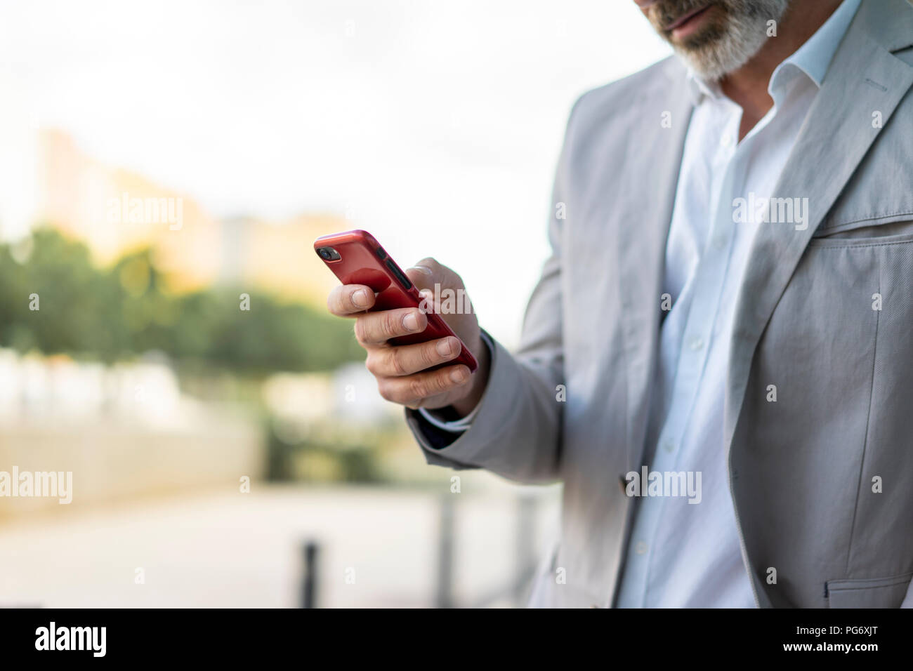 Businessman using smartphone outdoors, partial view Stock Photo