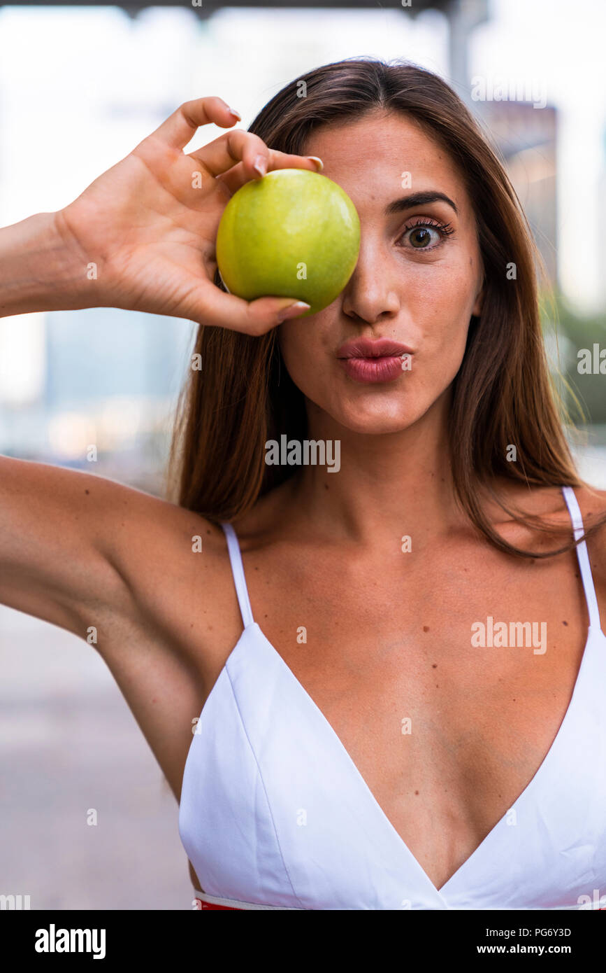 Portrait of attractive young woman wearing sports bra holding an apple Stock Photo